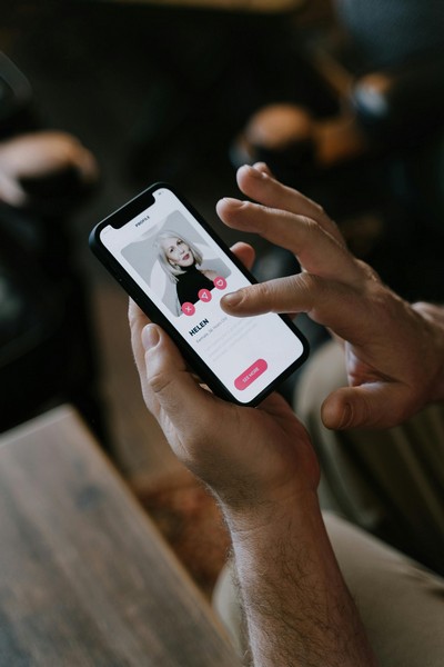 Muškarac koristi aplikaciju za online dejting na telefonu, pregledava profil žene na Tinderu