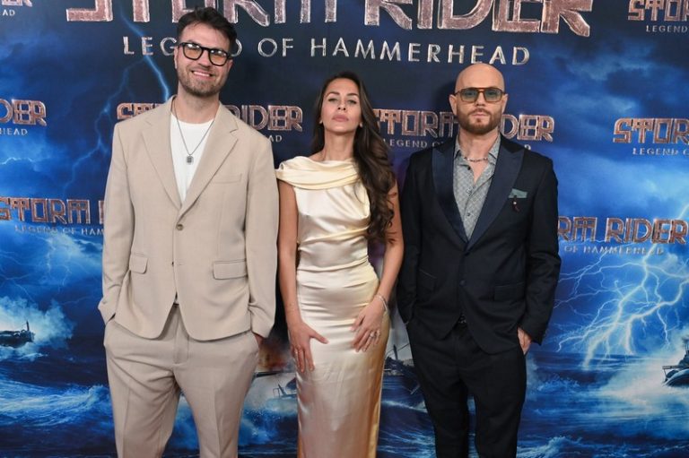 Troje glumaca i autora poziraju na crvenom tepihu ispred plakata filma „Storm Rider: Legend of Hammerhead“ na premijeri u Los Anđelesu.