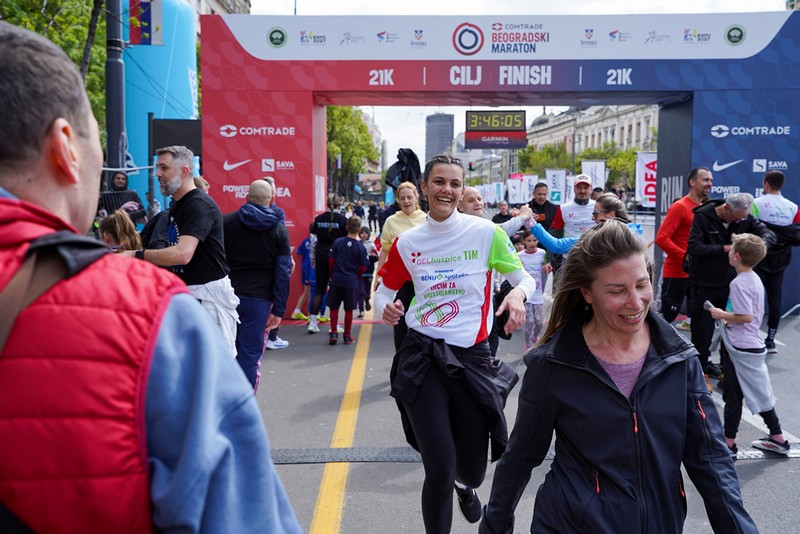 Trkačica BELhospice tima prolazi kroz cilj na Beogradskom maratonu okružena učesnicima i publikom, promovišući humanitarnu akciju za palijativnu negu