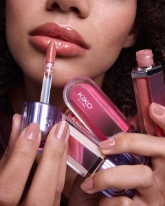 Model nanosi KIKO Milano 3D Hydra lip gloss aplikatorom, držeći više sjajnih proizvoda za usne u roze i nude nijansama, sa efektom visokog sjaja i hidriranih usana.