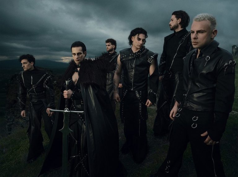 Grupa Lavina u tamnim scenskim kostimima stoji na otvorenom prostoru pod dramatičnim nebom, sa izraženim rock/metal vizuelnim identitetom i snažnom atmosferom benda.