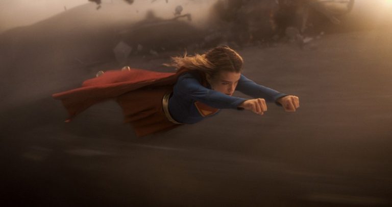 Supergirl leti velikom brzinom kroz vazduh u akcijskoj sceni iz filma, sa crvenim plaštom koji vijori iza nje, tokom epske avanture u novom DC spektaklu