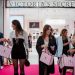 Kupci ispred prodavnice Victoria’s Secret sa roze kesama tokom svečanog otvaranja, uz crveni tepih i luksuzno uređen enterijer u pozadini.