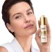 Žena sa čistim tenom drži Eucerin Hyaluron-Filler + Elasticity ultralaganu dnevnu kremu sa SPF 50+ u zlatnom pakovanju, predstavljajući anti-age negu za zrelu kožu.